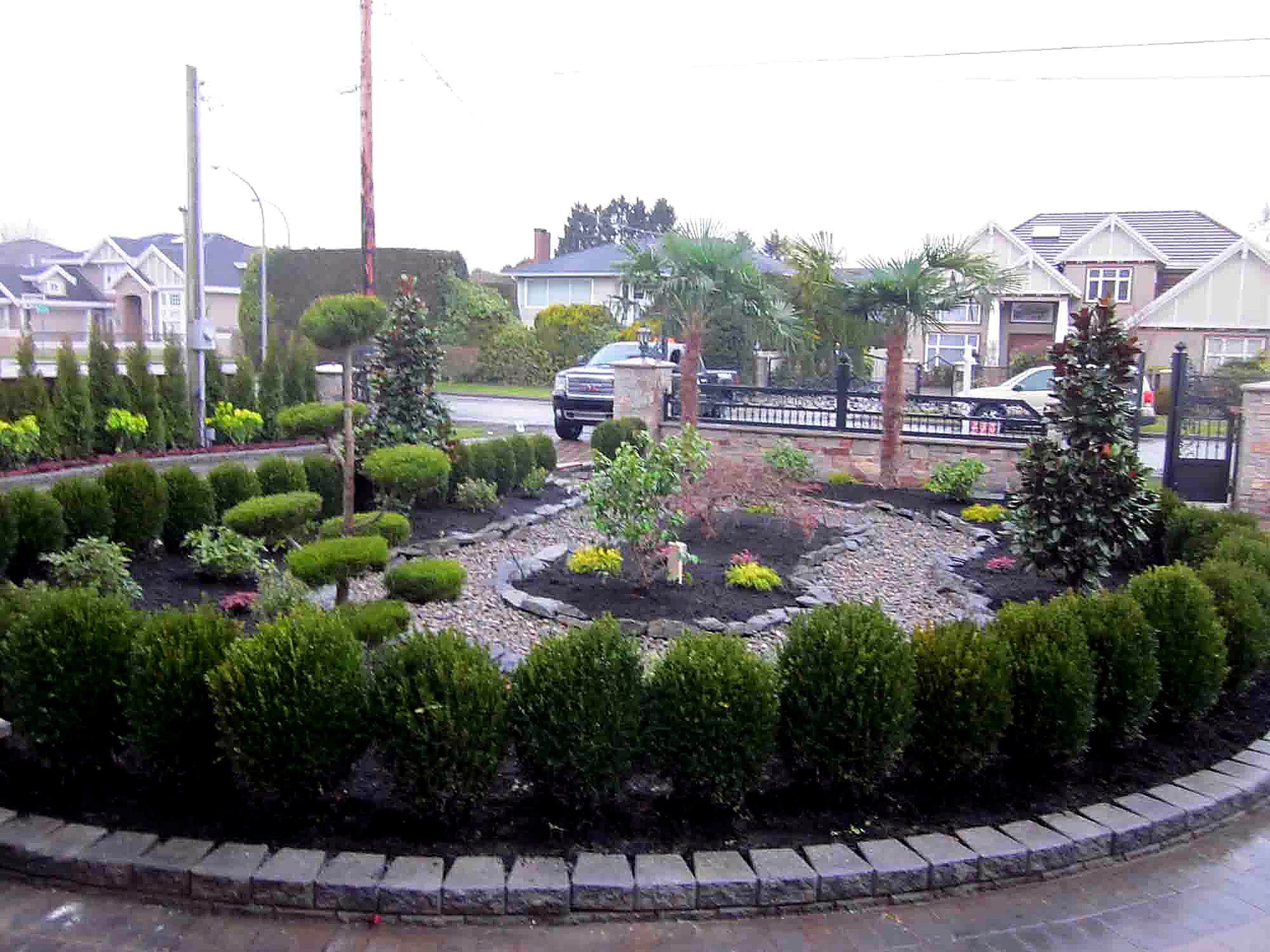 Circular boxwood garden bed with cobblestone curb